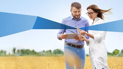 Zwei Personen stehen mit einem Tablet in einem Kornfeld